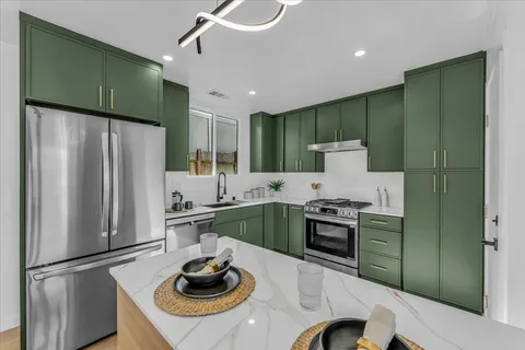 a kitchen with stainless steel appliances granite countertop a refrigerator a sink dishwasher a stove and a refrigerator with wooden floor