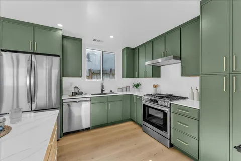 a kitchen with stainless steel appliances granite countertop a stove a sink and a refrigerator