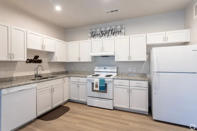 a kitchen with granite countertop white cabinets and white appliances