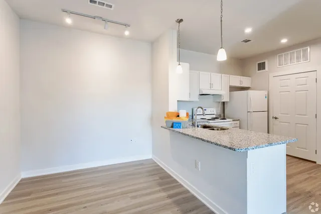 a kitchen with stainless steel appliances granite countertop a sink a stove a refrigerator and white cabinets with wooden floor