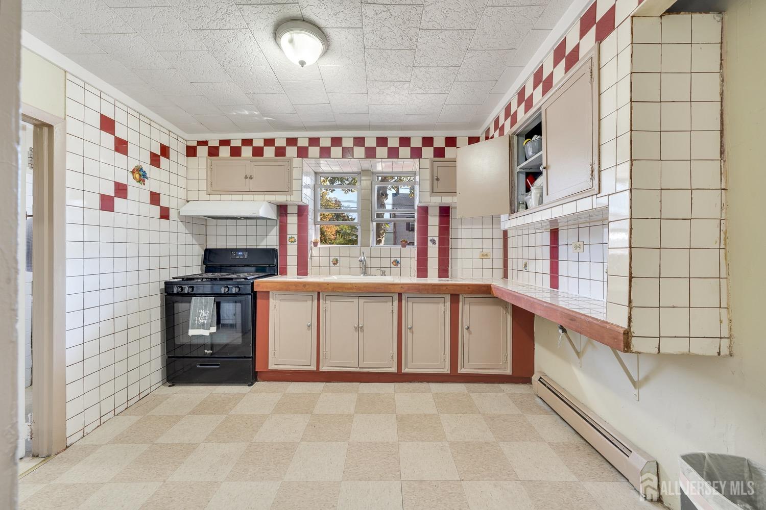 64 Commerce Street Perth Amboy, NJ 08861 - Photo 22 of 25 a large white kitchen with granite countertop a stove and a sink