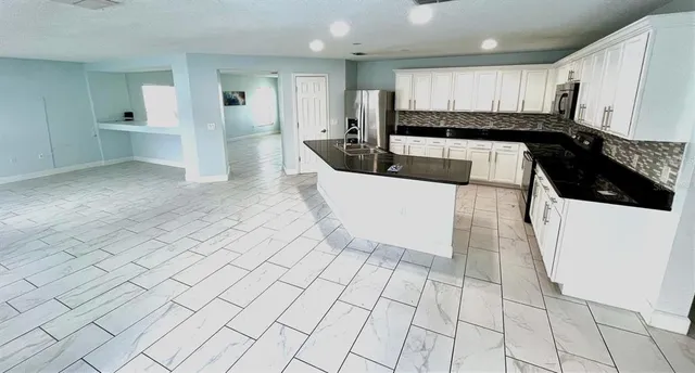 a large white kitchen with stainless steel appliances granite countertop a sink and cabinets