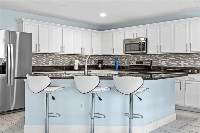 a kitchen with stainless steel appliances a sink a stove a refrigerator a counter space and cabinets