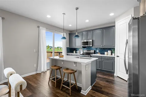 a kitchen with kitchen island stainless steel appliances a stove a sink a refrigerator cabinets and chairs