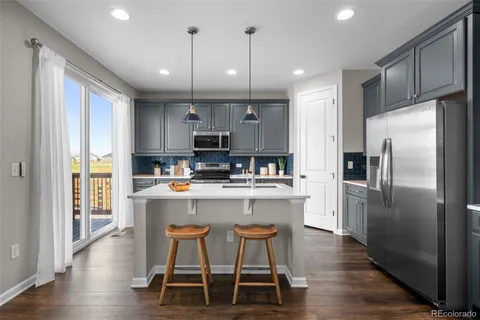 a kitchen with kitchen island a refrigerator and a stove top oven