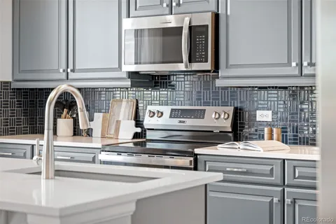 a kitchen with granite countertop a stove and a white cabinets
