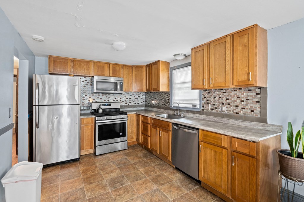 65 Wyvern Street Boston, MA 02131 - Photo 9 of 26 a kitchen with stainless steel appliances granite countertop a refrigerator a stove a sink and a microwave
