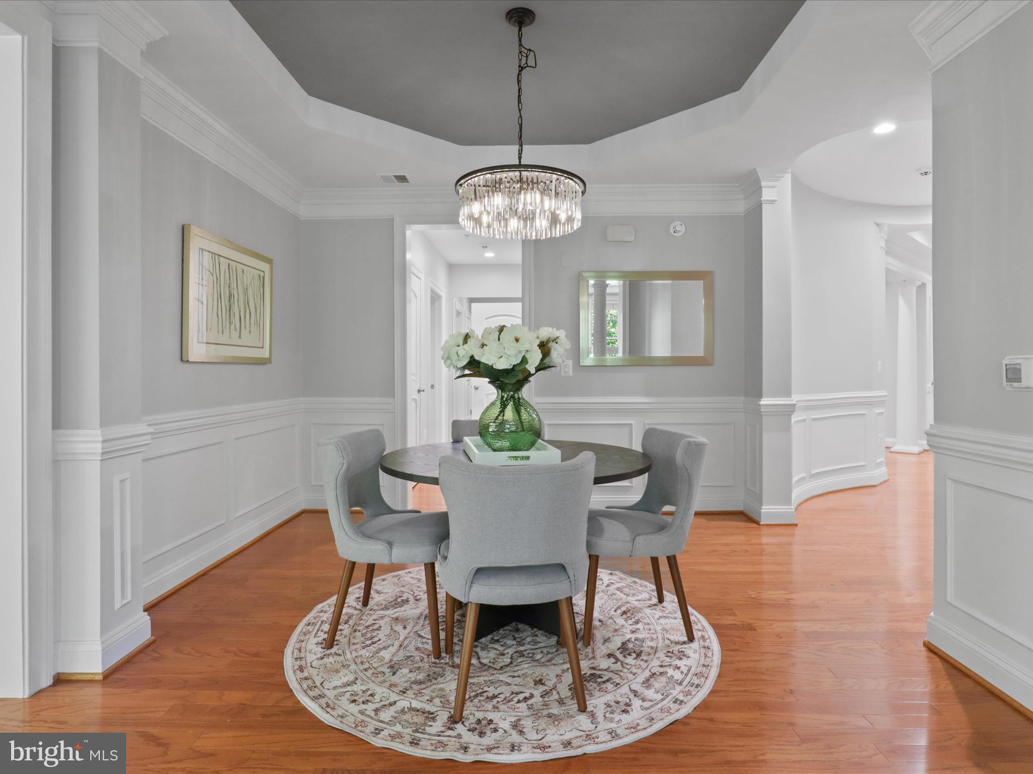1781 Chain Bridge Road, Unit 303 McLean, VA 22102 - Photo 20 of 56 a dining room with wooden floor a chandelier a wooden table and chairs