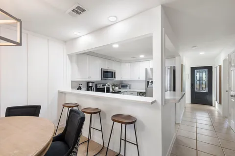 a kitchen with stainless steel appliances a refrigerator a stove a sink dishwasher and white cabinets with wooden floor