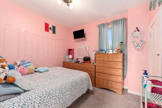 a bedroom with a bed and flat tv screen on the dresser