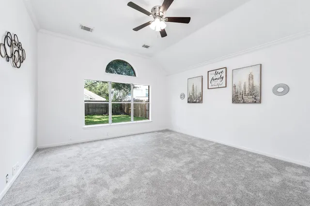 a view of an empty room with window and ceiling fan