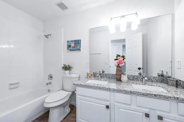 a bathroom with a granite countertop sink a toilet a mirror and shower