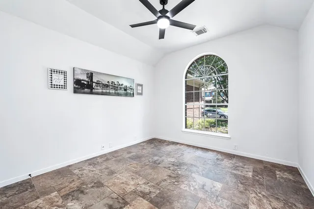 an empty room with windows and ceiling fan