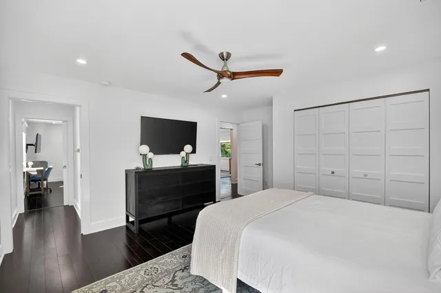 a bedroom with a bed and a flat tv screen on dresser