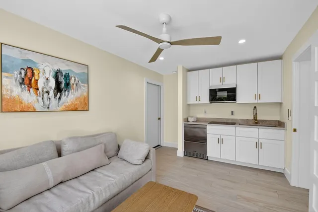 a living room with stainless steel appliances furniture and a kitchen view