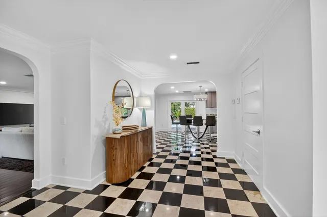 a living room with a black white checkered floor with a gaming machine and dining chairs