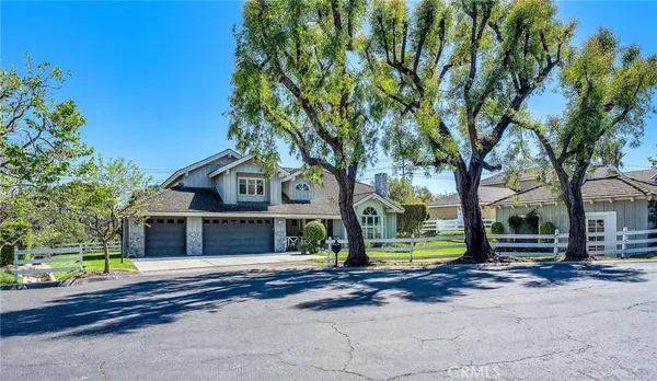 a view of a house with a large tree and wooden fence