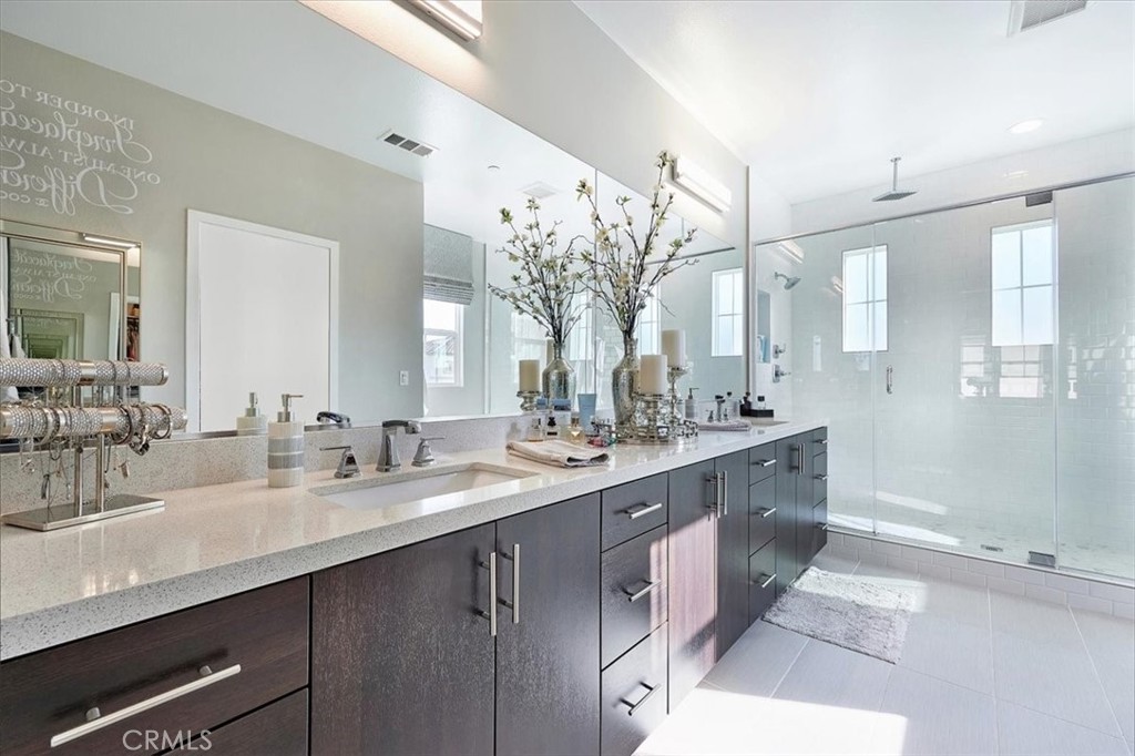 944 Sunlit Lane Costa Mesa, CA 92626 - Photo 36 of 71 a bathroom with double vanity sinks a large mirror and a shower