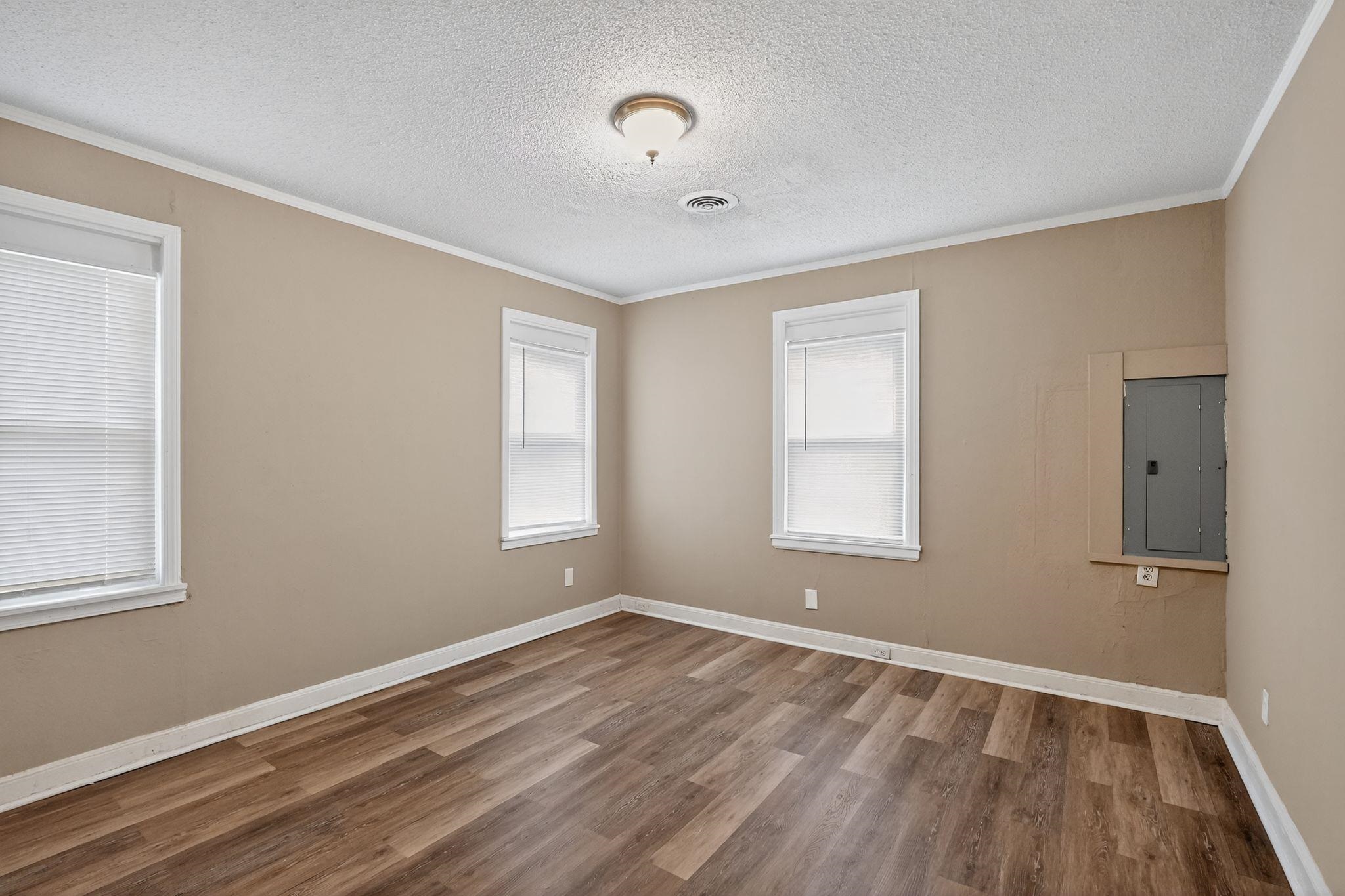 356 Hewlett Road Memphis, TN 38109 - Photo 18 of 30 Spare room featuring crown molding, a textured ceiling, electric panel, plenty of natural light, and wood finished floors
