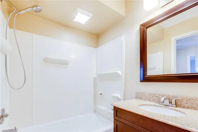 a bathroom with a granite countertop sink a mirror and a bathtub