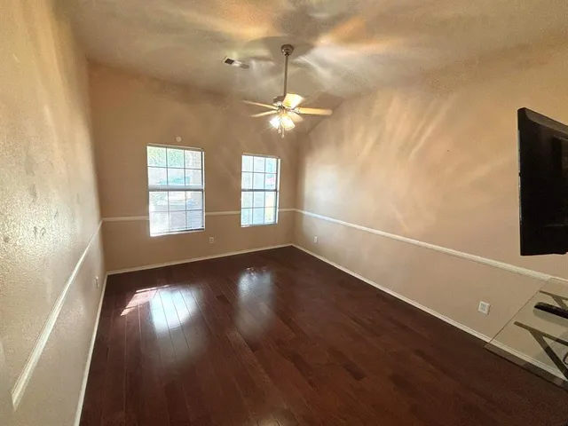 an empty room with wooden floor fan and windows