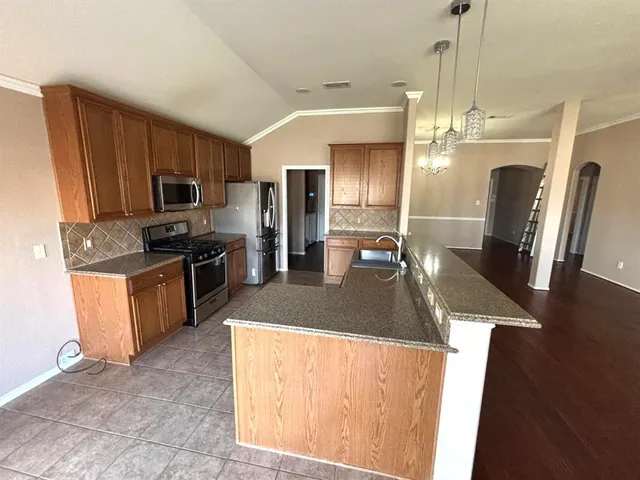 a kitchen with stainless steel appliances granite countertop a sink a stove a refrigerator a washer dryer and a refrigerator