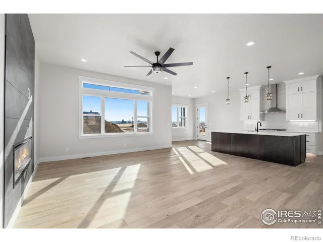 a living room with stainless steel appliances kitchen island a chandelier furniture a fireplace and a window