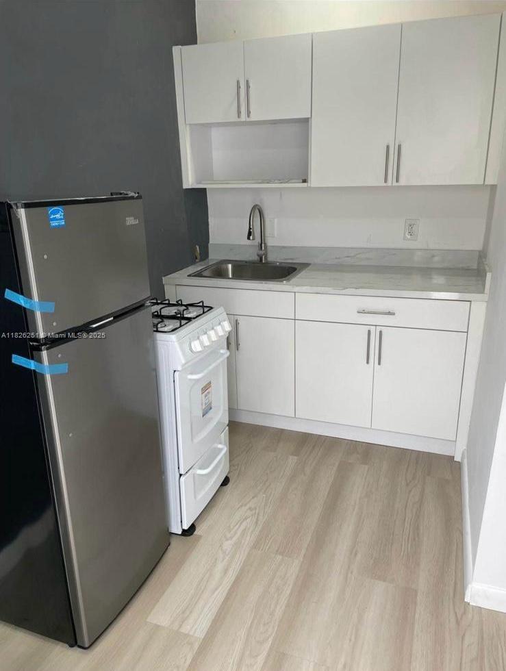 217 East 20th Street Hialeah, FL 33010 - Photo 19 of 22 a kitchen with white cabinets and white appliances