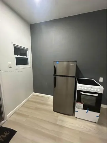 a room with a wooden floor and stainless steel appliances