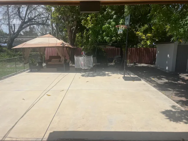 a backyard of a house with large trees and outdoor seating