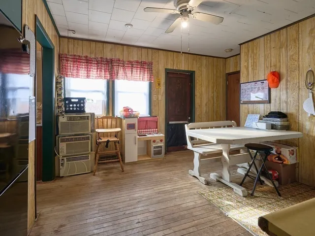 a open kitchen with stainless steel appliances granite countertop a stove top oven a refrigerator a dining table and chairs with wooden floor