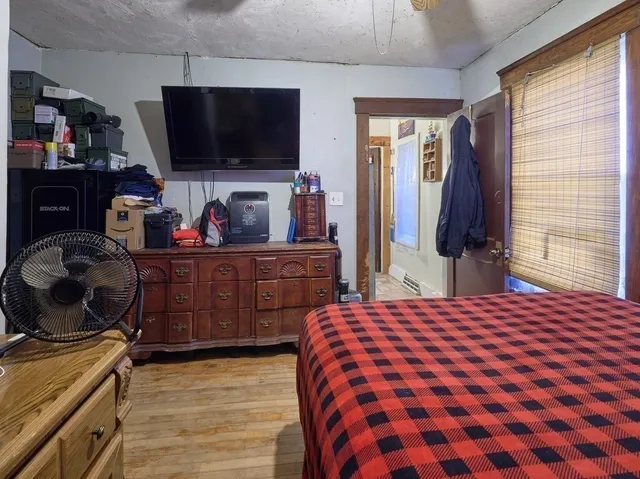 a bedroom with a bed and a flat tv screen on dresser