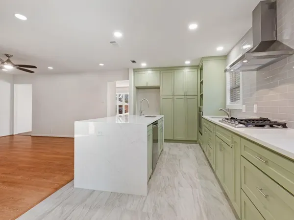 a large kitchen with stainless steel appliances a large counter top a stove and a refrigerator