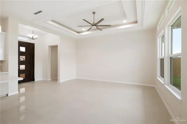 a view of an empty room with window and chandelier fan