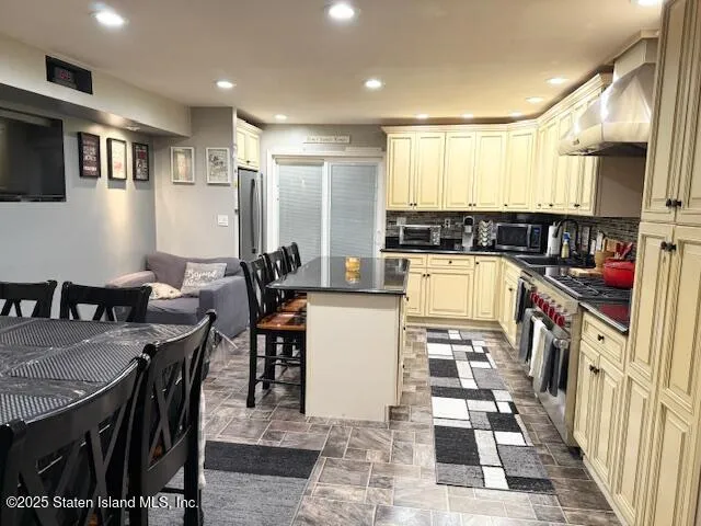 a kitchen with stainless steel appliances granite countertop a table chairs and a refrigerator