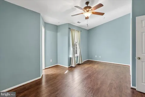 an empty room with wooden floor and a ceiling fan