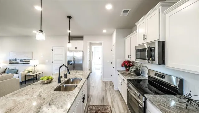 a kitchen that has a lot of cabinets a sink and appliances in it