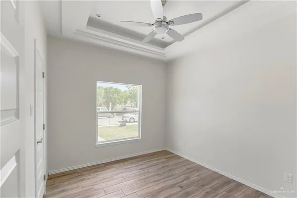 an empty room with wooden floor chandelier fan and windows