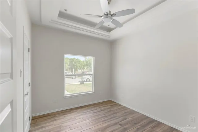 an empty room with wooden floor chandelier fan and windows