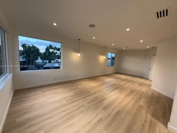 a view of empty room with wooden floor and window