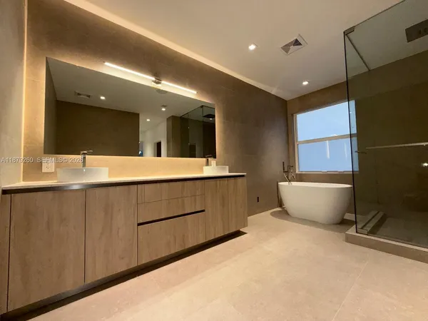 a bathroom with a double vanity sink a mirror and a bathtub