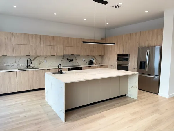 a kitchen with kitchen island a counter top a sink stainless steel appliances and cabinets