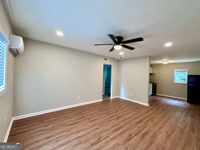 a view of an empty room with wooden floor and a ceiling fan
