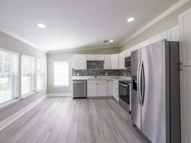 a kitchen with a refrigerator a sink and wooden floor