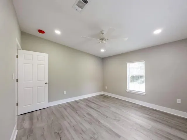 an empty room with wooden floor and window