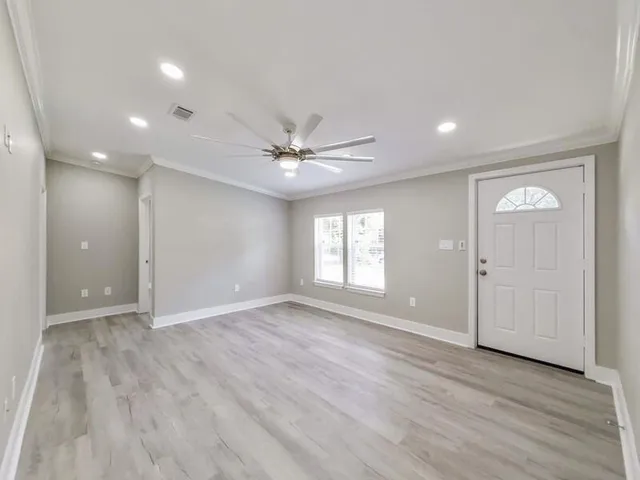 a view of an empty room with wooden floor and a window
