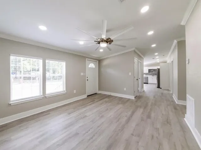 a view of an empty room with a window and a kitchen