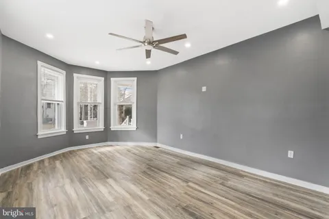 a view of empty room with wooden floor and fan