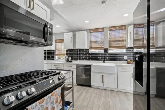 a kitchen with stainless steel appliances a sink a stove and cabinets