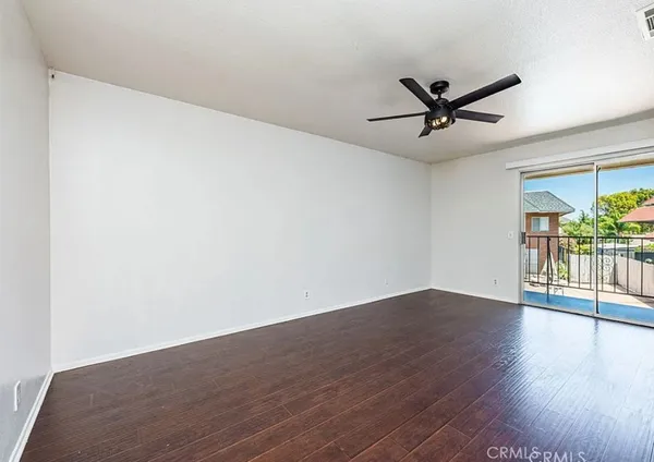 a view of a big room with wooden floor a ceiling fan and windows